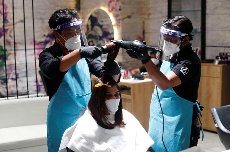 A woman gets his haircut done by beauticians wearing personal protective equipment (PPE) inside a beauty salon, after authorities allowed them to open, during an extended nationwide lockdown to slow the spread of the coronavirus disease (COVID-19), in New Delhi, India, June 3, 2020. REUTERS/Adnan Abidi